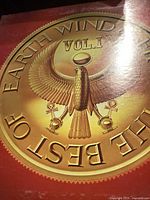 Front cover of the vinyl record showing golden emblem with Egyptian designed bird and 'Earth Wind The Best Vol. 1' text.