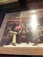 Front view of the Toulouse Street vinyl record sleeve by The Doobie Brothers, showing band members and dog in a room.