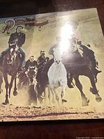 Front cover of The Doobie Brothers Stampede vinyl record showing horseback riders in motion.