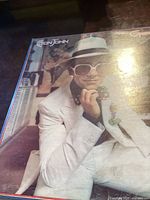 Photo showing front cover of Elton John Greatest Hits vinyl record with Elton John in white suit and sunglasses.