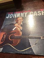 Front cover of 'The Fabulous Johnny Cash' vinyl record album showing Johnny Cash with guitar and title in large letters. The cover has a faint scratch visible.