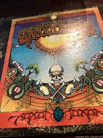 Colorful Grateful Dead album cover showing psychedelic art with skeleton and sun motif