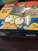 Top box view showing Simpsons artwork and plastic window display of chess pieces.