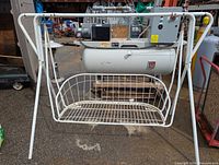 Metal patio swing frame with white coating, showing structural integrity and signs of wear. Cushions included with visible tears and damage.