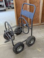 Front angle view of Liberty garden hose cart showing metal frame, hose reel and pneumatic tires.
