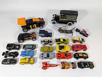 Top view showing 22 assorted toy cars mostly diecast with varying colors including black, yellow, orange, blue, red and silver. Large black and orange race car is prominent.