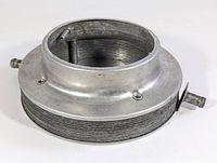 Side angle view of OEM Volvo Penta flame arrestor shield showing coil wire mesh and metal housing with nozzles and mounting bracket.