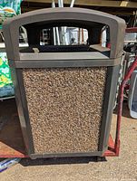 Front view showing rock gravel panel design on the trash can exterior with dark brown frame.