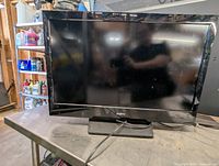 Front view of the Sanyo 32-inch television showing the entire screen and stand, dusty without remote.