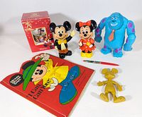 Overview of all items including Mickey, Minnie, Sulley figures, Mickey gold figurine, snowglobe box, cloth book and pen