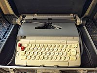 Full view of the vintage Smith Corona electric typewriter positioned inside a protective carrying case, showing keys, carriage area, and cord.