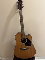 Full view of Takamine Jasmine acoustic guitar with natural finish and black pickguard, showing overall condition and missing one string.