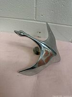 Side angled view showing sleek polished aluminum flying goose sculpture with smooth contours and reflective surface.