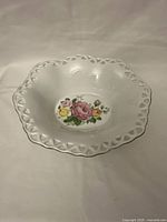 Top angled photo of white porcelain bowl with lattice rim and floral pattern inside base.