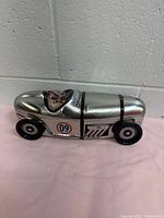 Side view of silver metal race car tin with driver figure and number decal 09