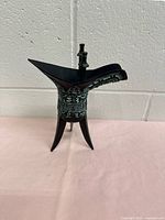 Side view of Chinese bronze Jue bowl showing spout, handle, and tripod legs with detailed engravings.