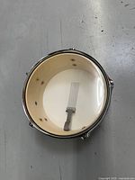 Top-down view of drum interior showing natural wood finish and metal snare wires attached underneath the drumhead.