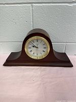 Full frontal view of Bulova Annette II fireplace mantel clock showing wooden case and brass bezel clock face.