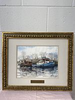 Full frontal photo of the framed painting showing the image of two boats on water with trees in the background. The frame is ornate and gilded.