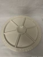 Top view of the white porcelain serving dish showing six divided sections with herb labels embossed around the edge.