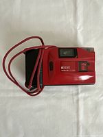 Top view of red Ricoh YF-20 compact camera showing lens, viewfinder, and front panel with model details.