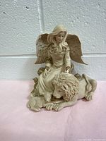 Full view of the angel figurine music box featuring an angel seated with a lamb and lion, showing overall design and size.