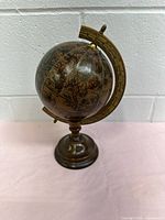 Full view of the vintage globe with antique map and brass-colored meridian on brown base