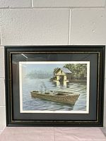 Full view of the framed print showing the boat and boathouse scene on water in wood frame