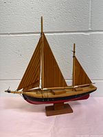 Side angle view of the handcrafted vintage wooden sailboat model showing the hull, sails and rigging details.