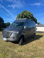 Front three-quarter view of dark grey 2021 Mercedes-Benz Sprinter camper van on grass
