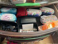 Drawer view showing multiple eyewear cases, black sunglasses, orange novelty glasses