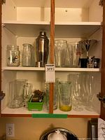 Cabinet shelves with majority of glassware and stainless pieces visible