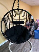 Full view of hanging egg chair with cushion on stand