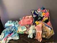 Table with assorted Care Bears items, plush bear, notebook, pencil cases, clothing, gloves, tights, swimsuit visible