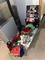 Wide view showing artificial tree box, plush ornaments box, string lights, Santa figure, runner, gift wrap