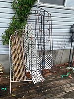 Group shot of metal trellises, bamboo stakes, lattice panels leaning against house