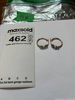 Pair of gold hoop earrings with blue stones beside lot card