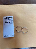 Overall view of hoop earrings beside lot tag