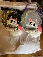 Front view of both cat-themed round handbags