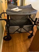 Full view of gray Jeep stroller wagon folded open with canopy attached