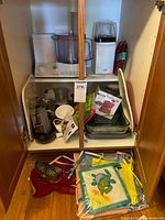 Cabinet view showing appliances, pans, glass bakeware, textiles