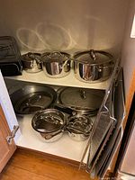 Cabinet showing Lagostina pots, lids, frying pan, pan organizer, baking sheets, wire racks