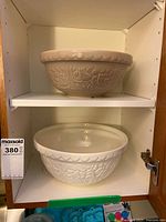 Two Mason Cash embossed mixing bowls on cabinet shelves
