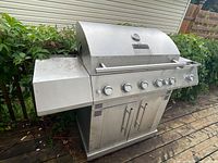 Front view of stainless steel Master Forge propane grill showing main structure and side shelf