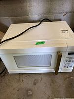 Front and top view of white microwave showing handle, window, control panel and power cord