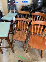 Group shot showing two aqua-seat stools and four wooden spindle-back chairs