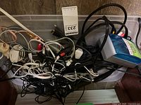 Top view of bin containing tangled cables and charger