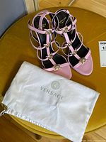 Top view of pink Versace strappy sandals with dust bag