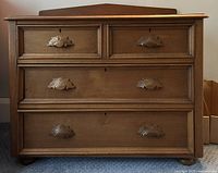 Front view of antique pine washstand showing four drawers and carved wooden handles.