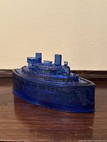 Front angle view of the blue pressed glass battleship candy dish showing details on top and hull with embossed text.